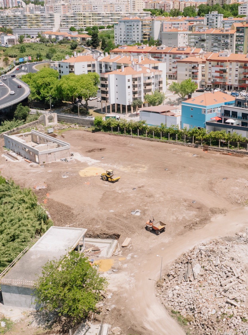 Imagem aérea da área em obras do futuro Parque Urbano da Cidade, em Odivelas, mostrando maquinaria em operação, estruturas em recuperação e envolvente