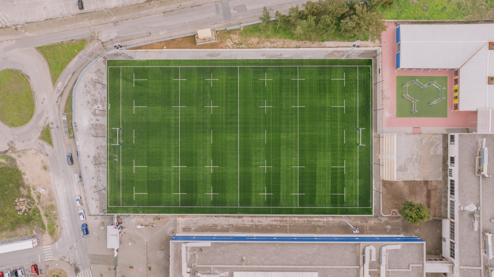 Campo de rugby da Escola Visconde Juromenha visto de cima, com relvado sintético completo e linhas demarcadas.