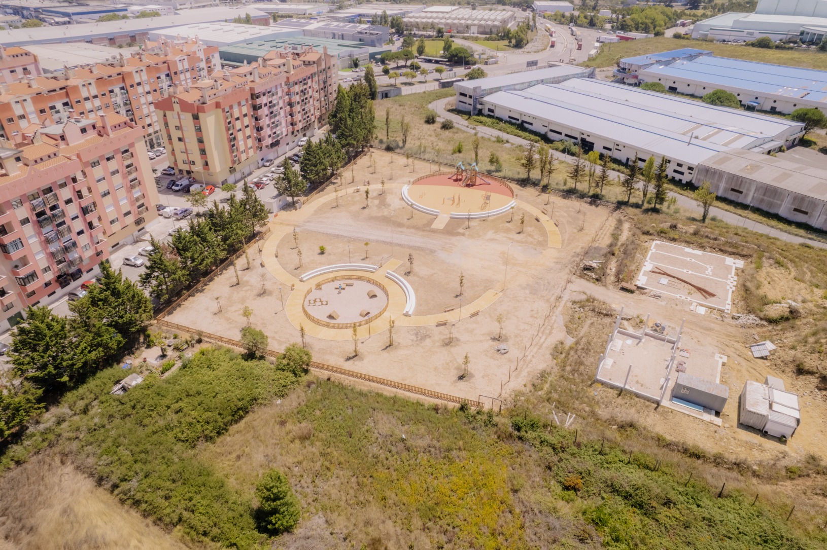 Parque de lazer e canino com parque infantil numa área ciruclar e com ajardinamentos ao redor
