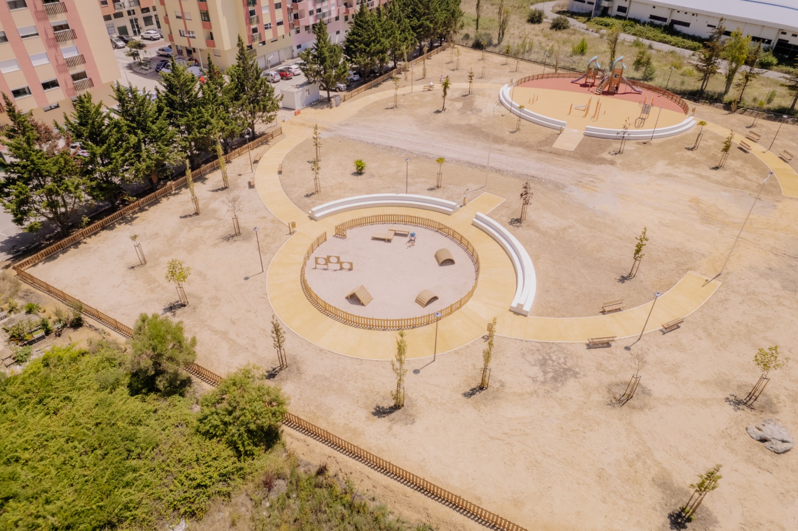 Parque de lazer e canino com parque infantil numa área ciruclar e com ajardinamentos ao redor